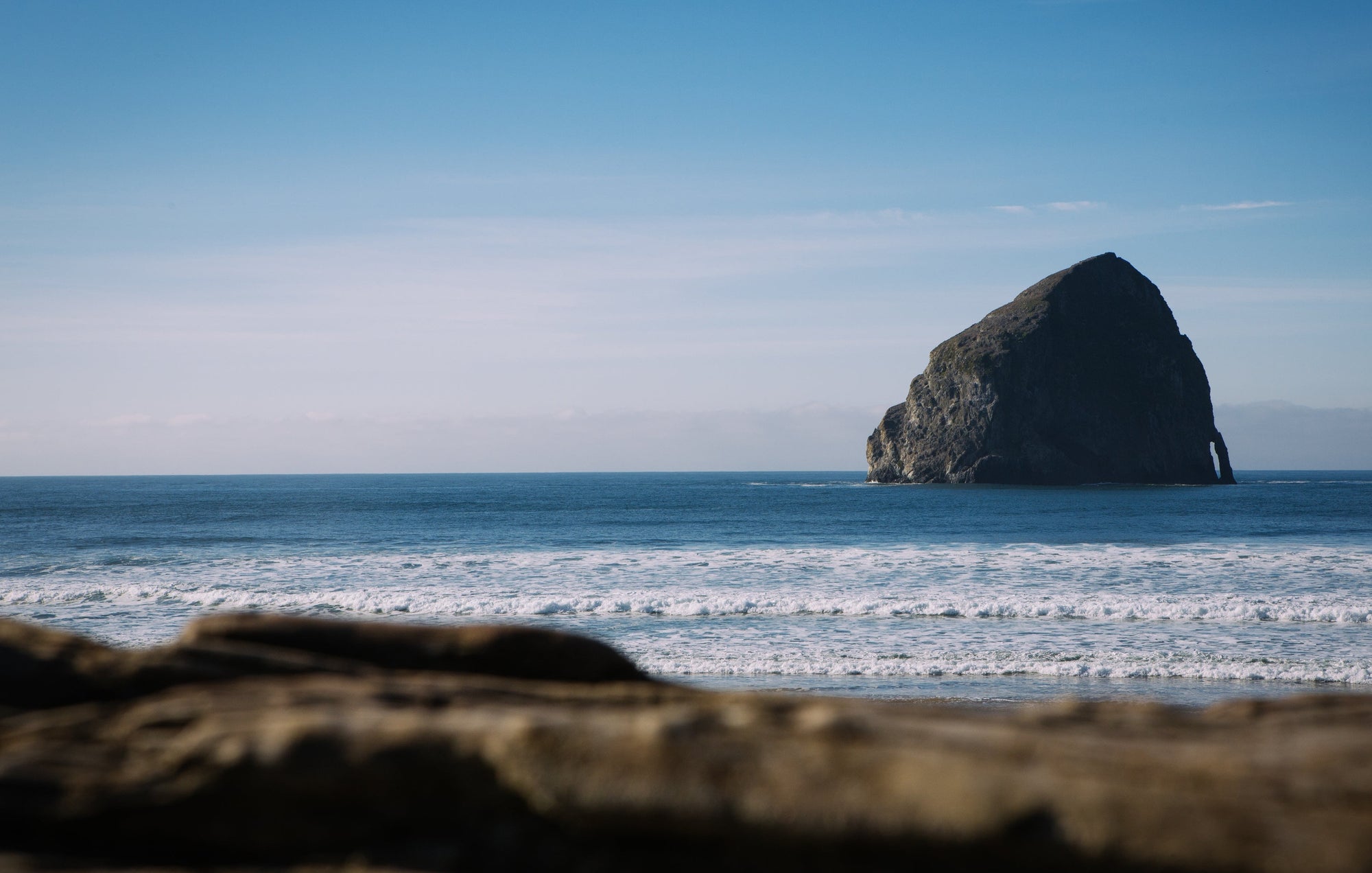 Isolated rock formation in the middle of the ocean with a clear blue sky.