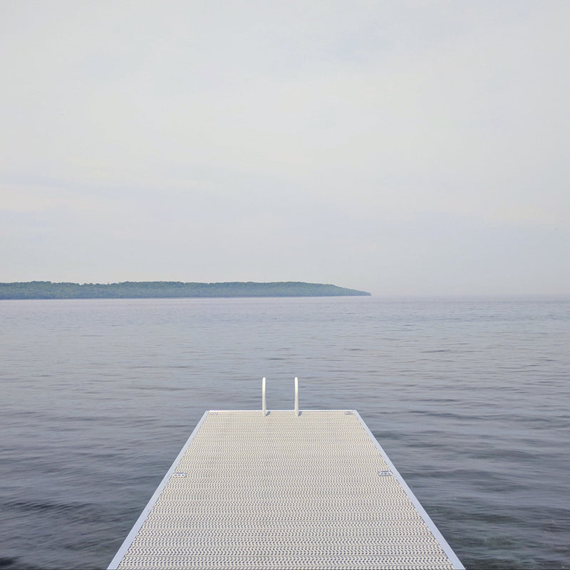 Long metal dock extending into a calm body of water with a clear sky.